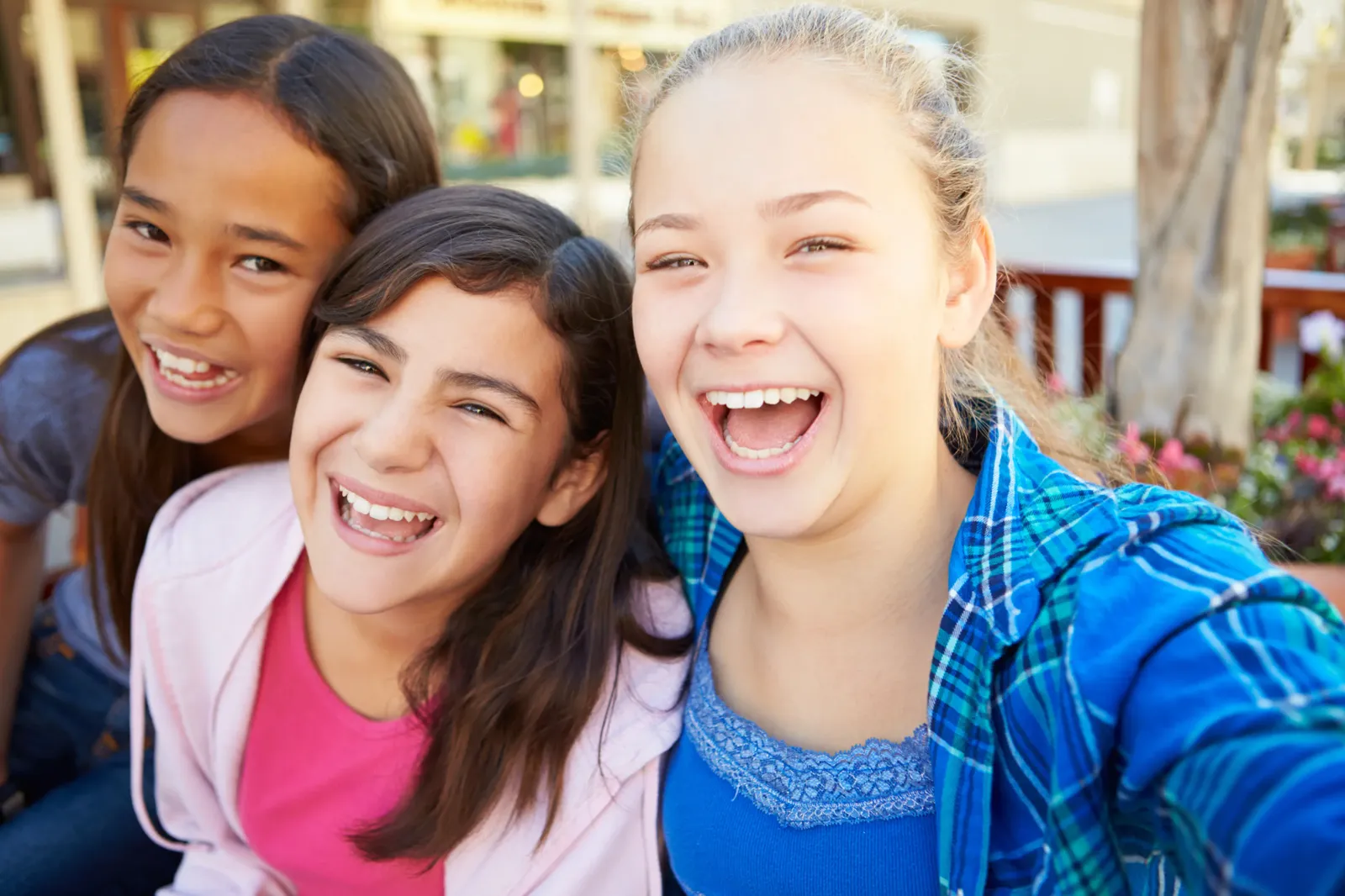 Tres niñas preadolescentes riendo juntas, representando los primeros pasos de independencia que ēllu acompaña con seguridad y privacidad