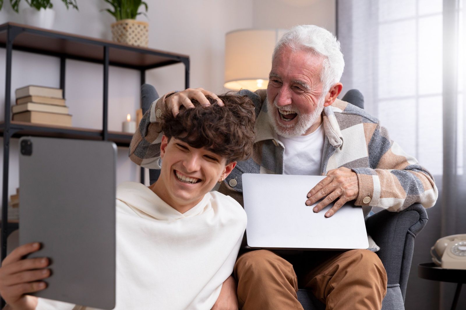 abuelo y nieto en el sofa de casa hablando con su padre por el ipad