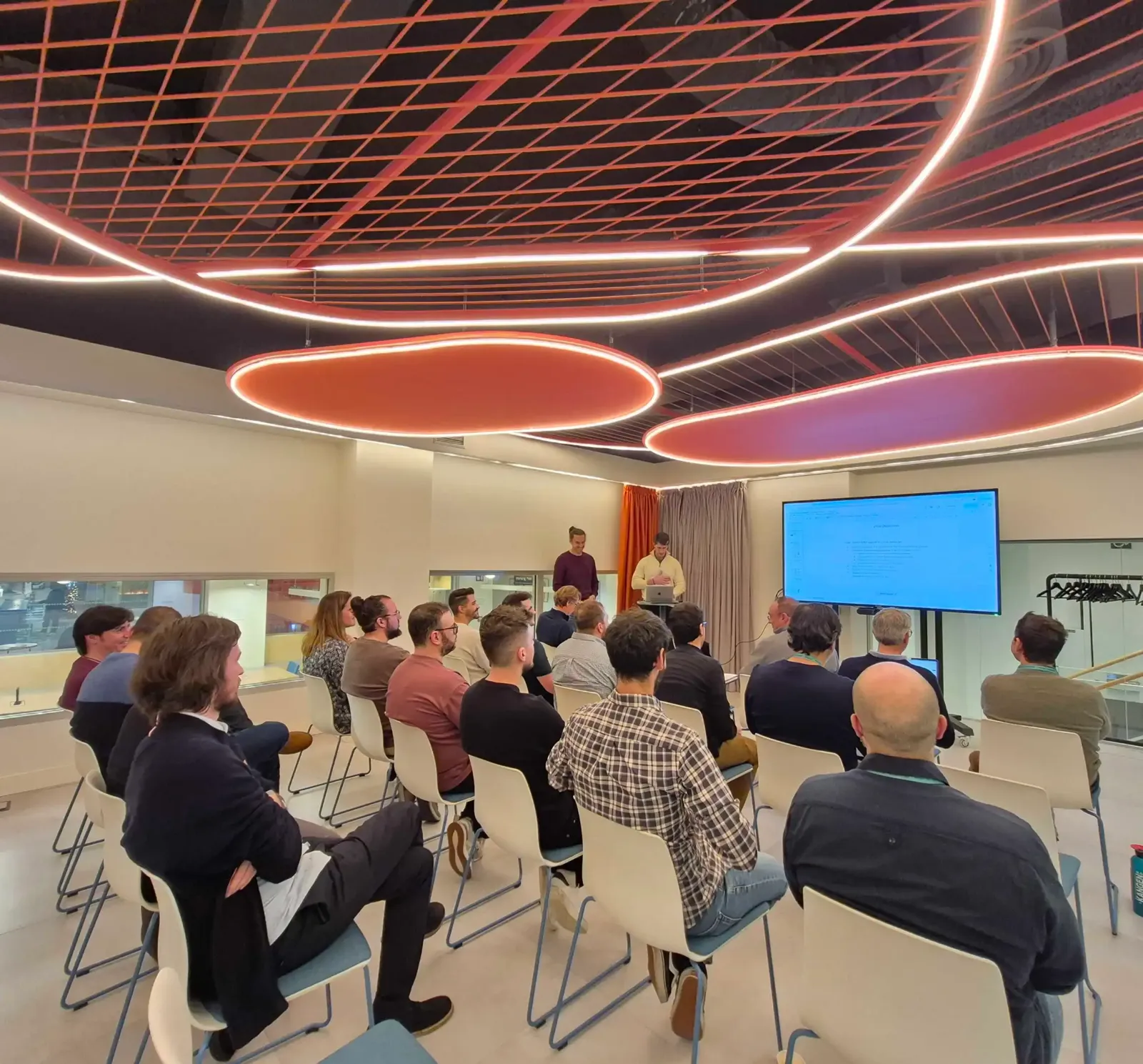 Equipo de ellu reunido en una presentación interna en una sala moderna, reflejo del ambiente de innovación y cultura de trabajo de la empresa