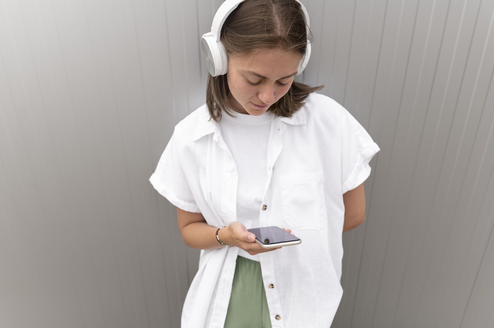 Chica joven con cascos mirando el móvil, primer smartphone adolescente